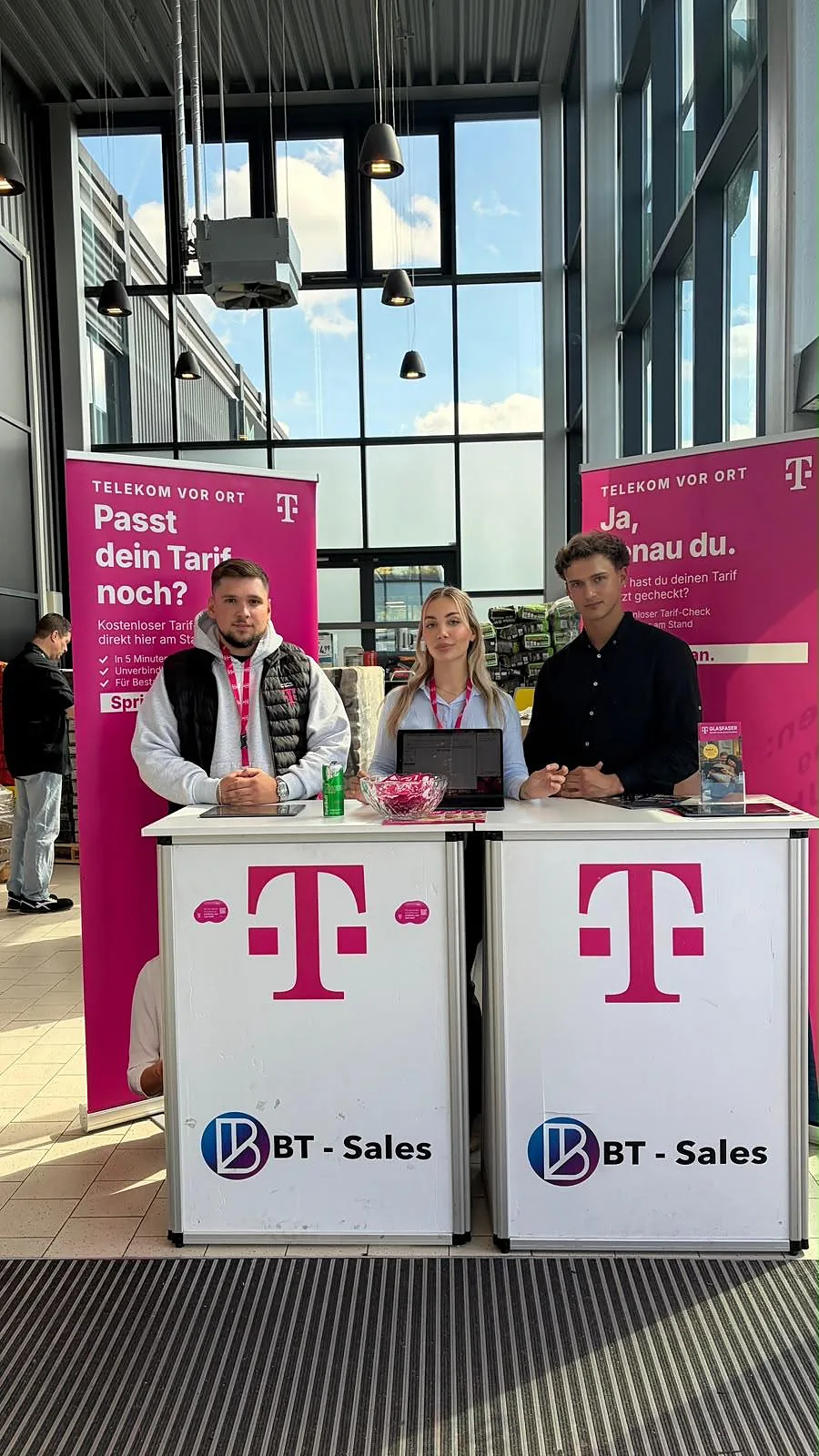 Drei Promoter gemeinsam hinter zwei Ständen der Telekom